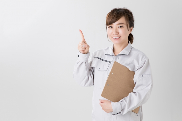 クリップボードを持った作業着の女性